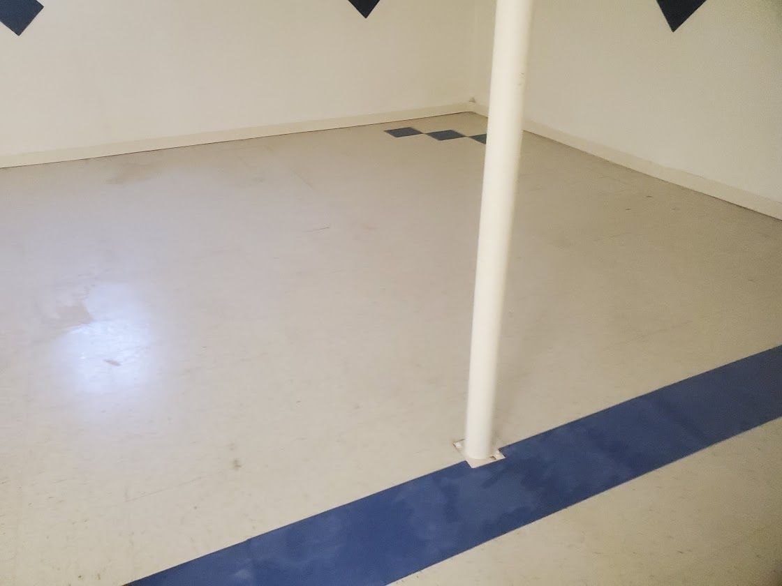 Empty light-colored room with a white support pole and blue floor trim.