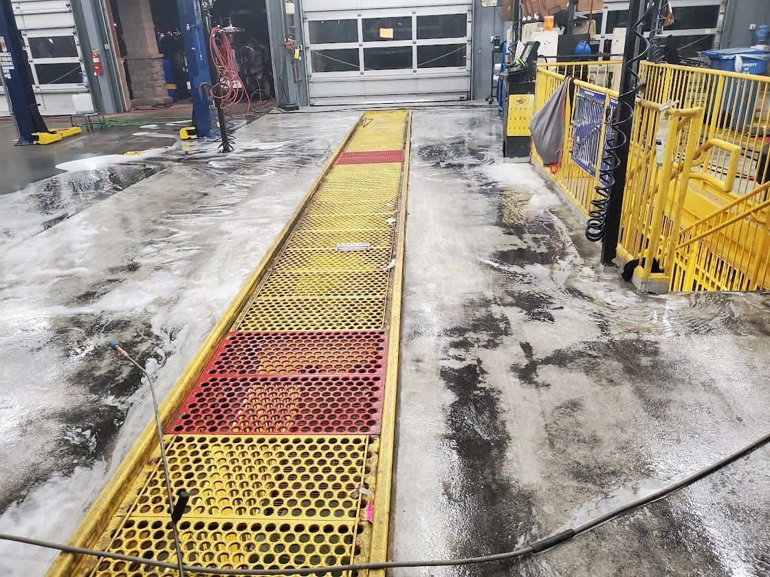 Yellow grated walkway on a wet industrial floor near a garage door and safety barriers