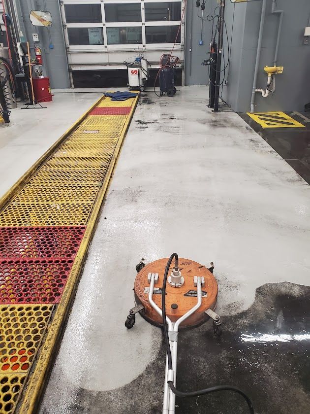 Industrial garage with wet floor, orange cleaning machine, and long yellow-red grating walkway