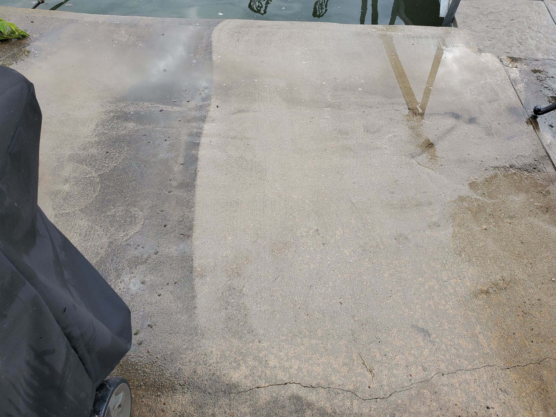 Concrete dock ramp beside water, with a dark fabric edge on the left and a rope at the top.