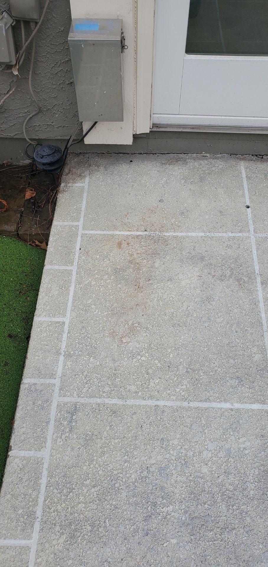 Front walkway with light gray pavers leading to a white door beside a utility box and mulch border