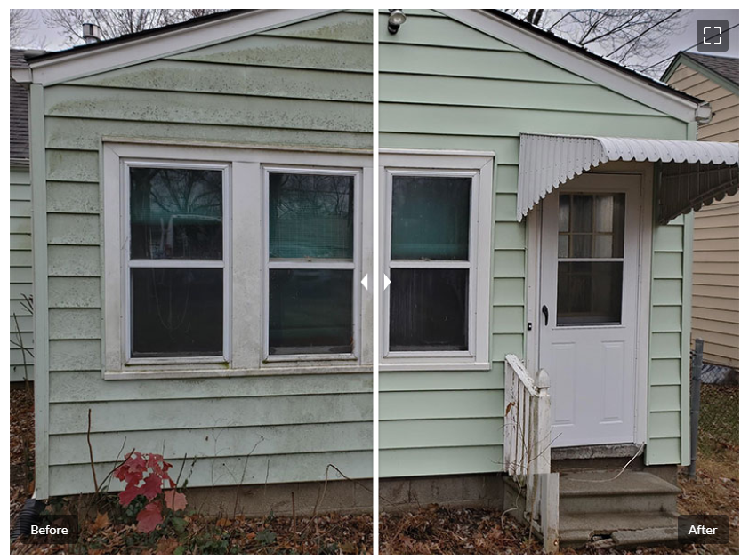 Light green house exterior with three front windows and a small white awning over the entry door.