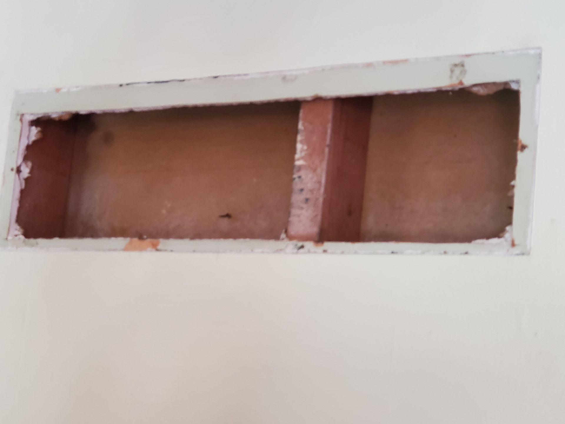 Rectangular wall opening with exposed brown interior framing and white plaster edges