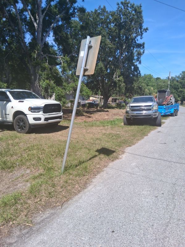 Roadside scene with parked white SUV, silver truck, and blue trailer beside a grassy shoulder and trees