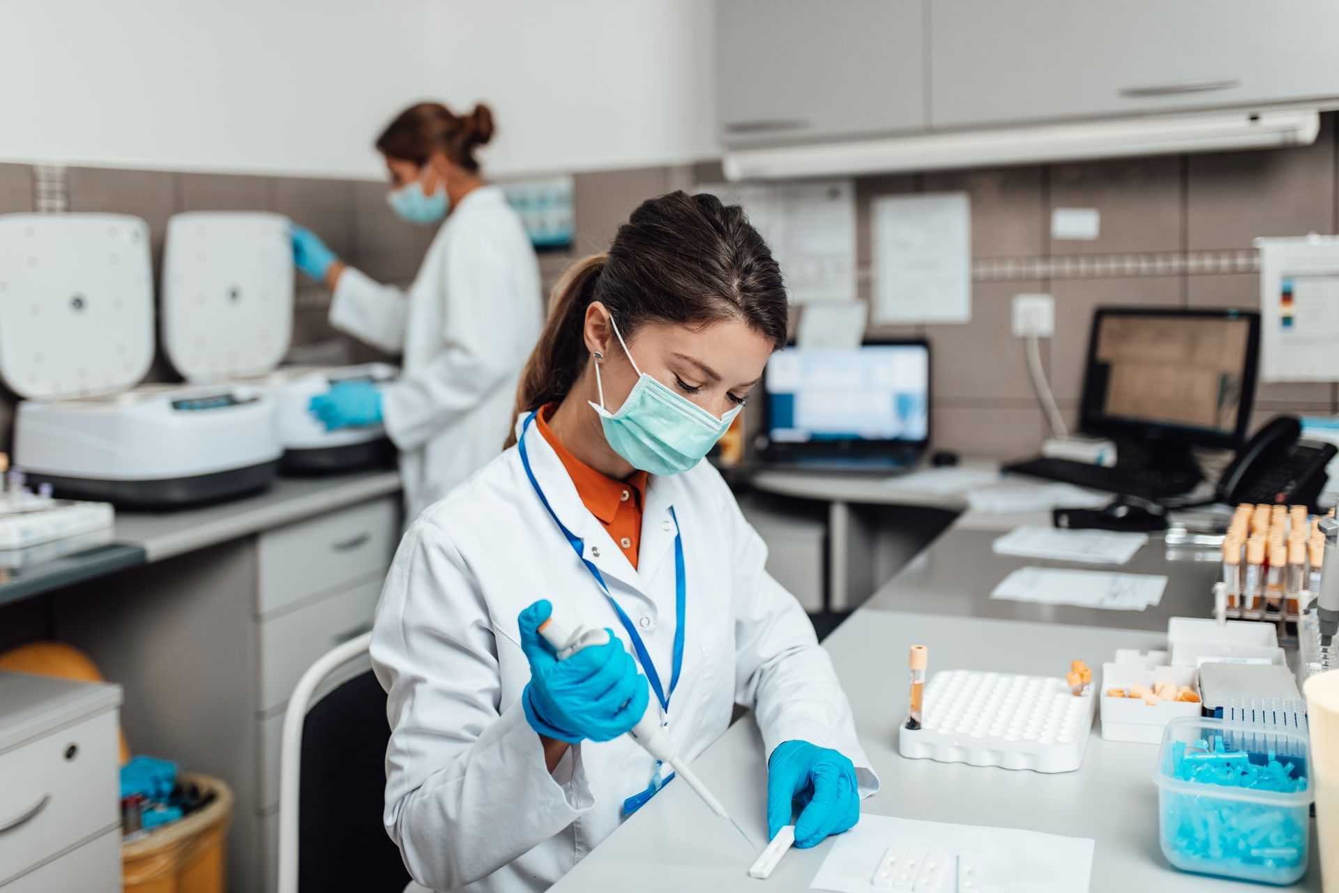 A female scientist wearing a mask and gloves is working in a laboratory.