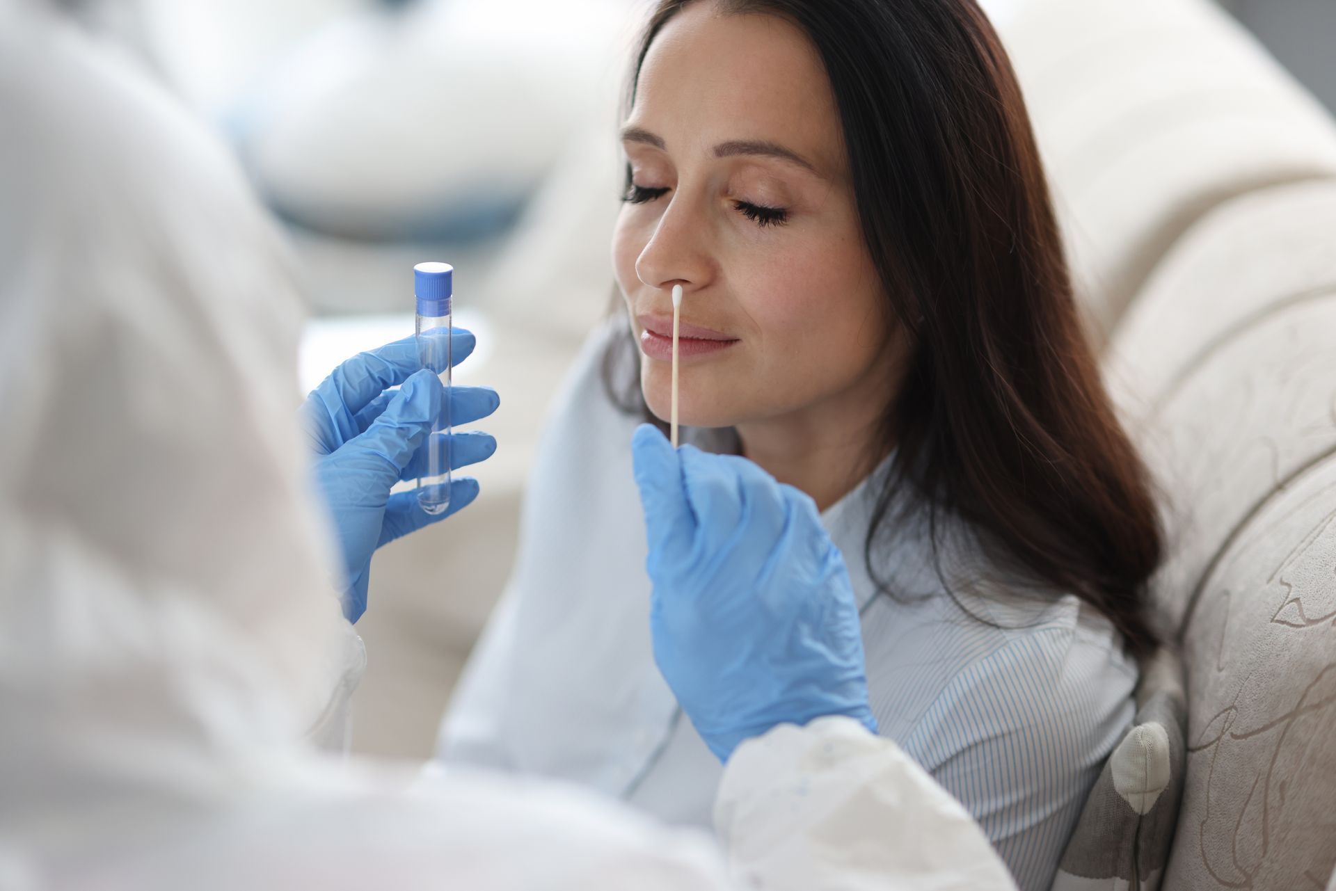 A woman is getting a nasal swab from a doctor.