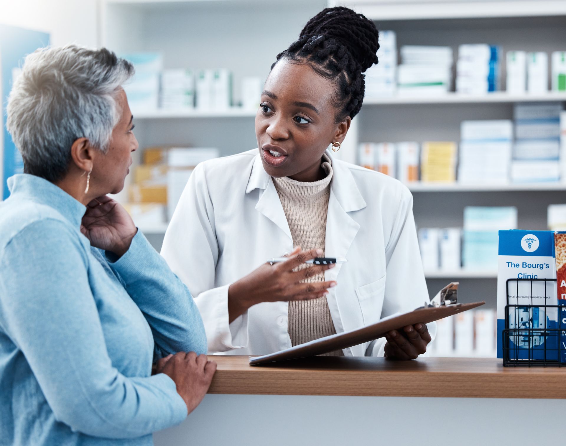 A female pharmacist is talking to an older woman in a pharmacy.