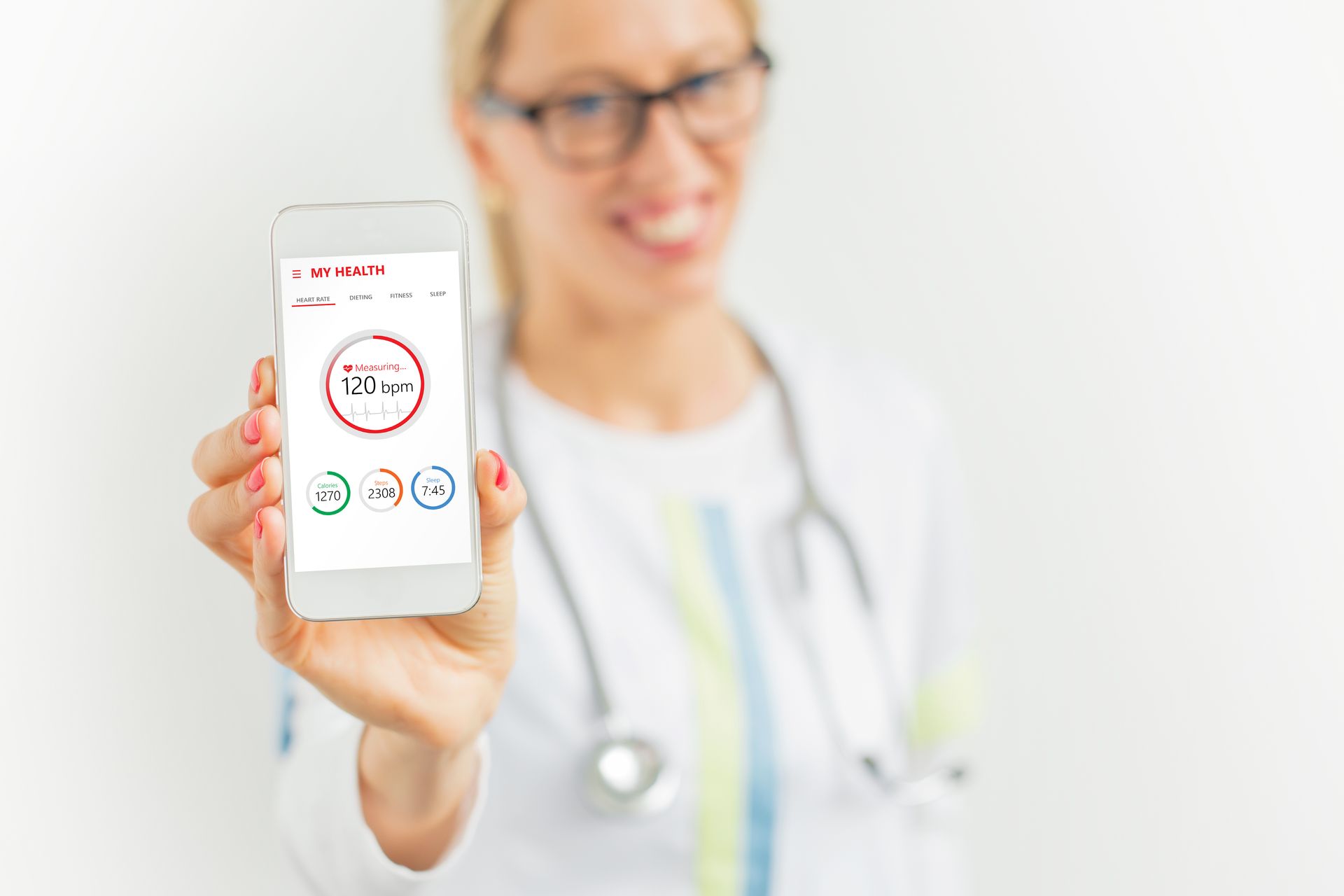 A female doctor is holding a cell phone in her hand.