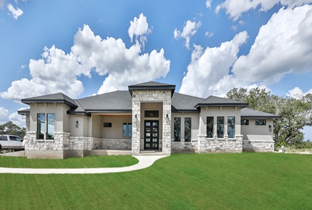 A large house with a lot of windows is sitting on top of a lush green lawn.