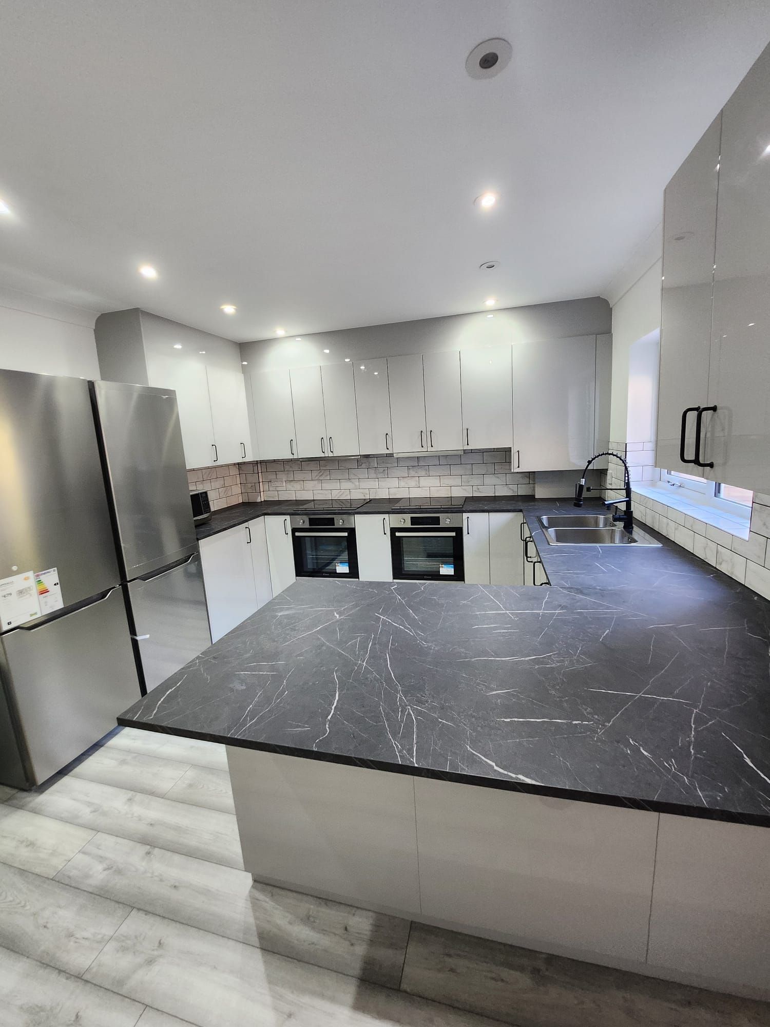 A kitchen with stainless steel appliances and a black counter top.