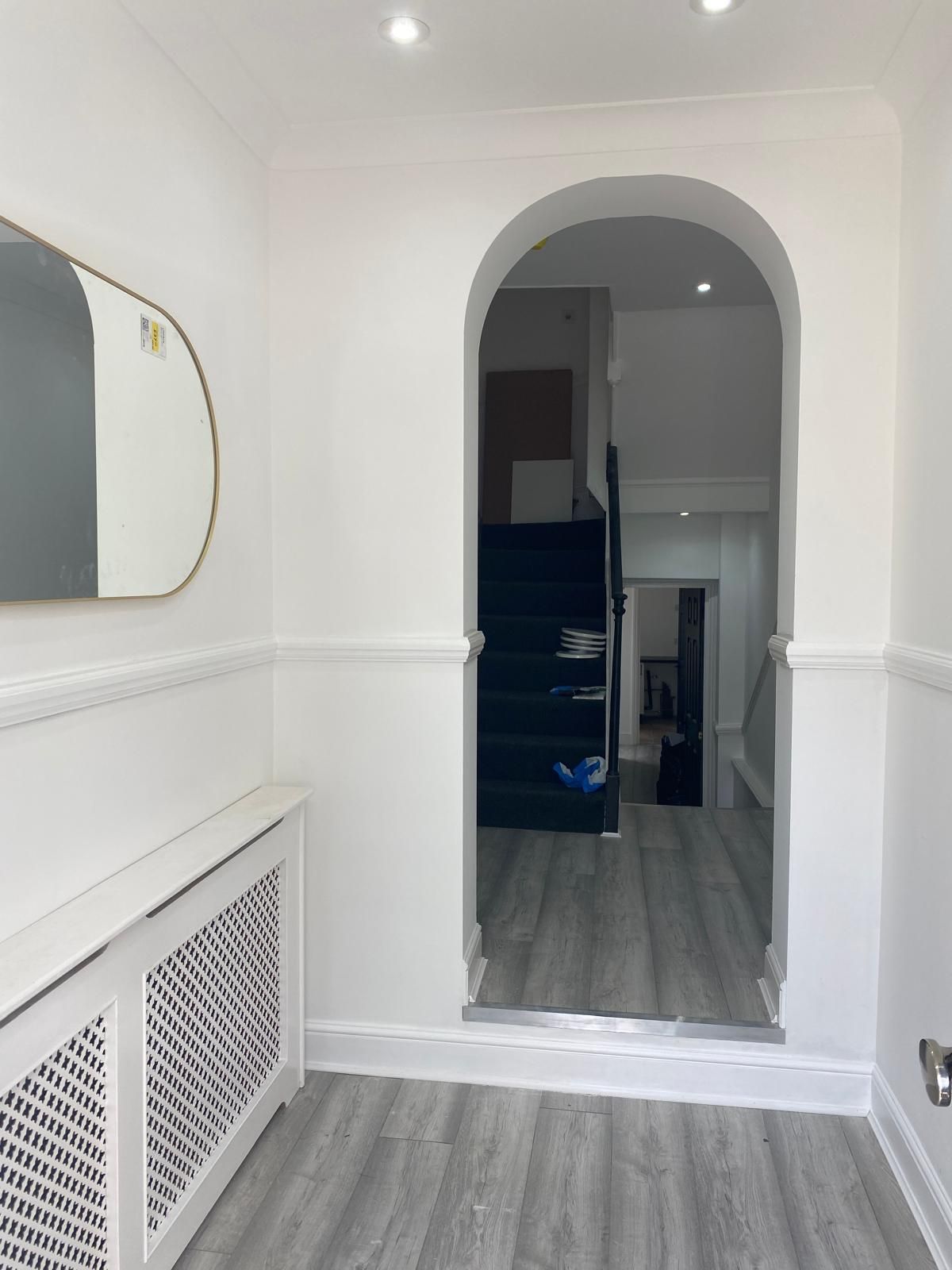 A hallway with a mirror and stairs in the background