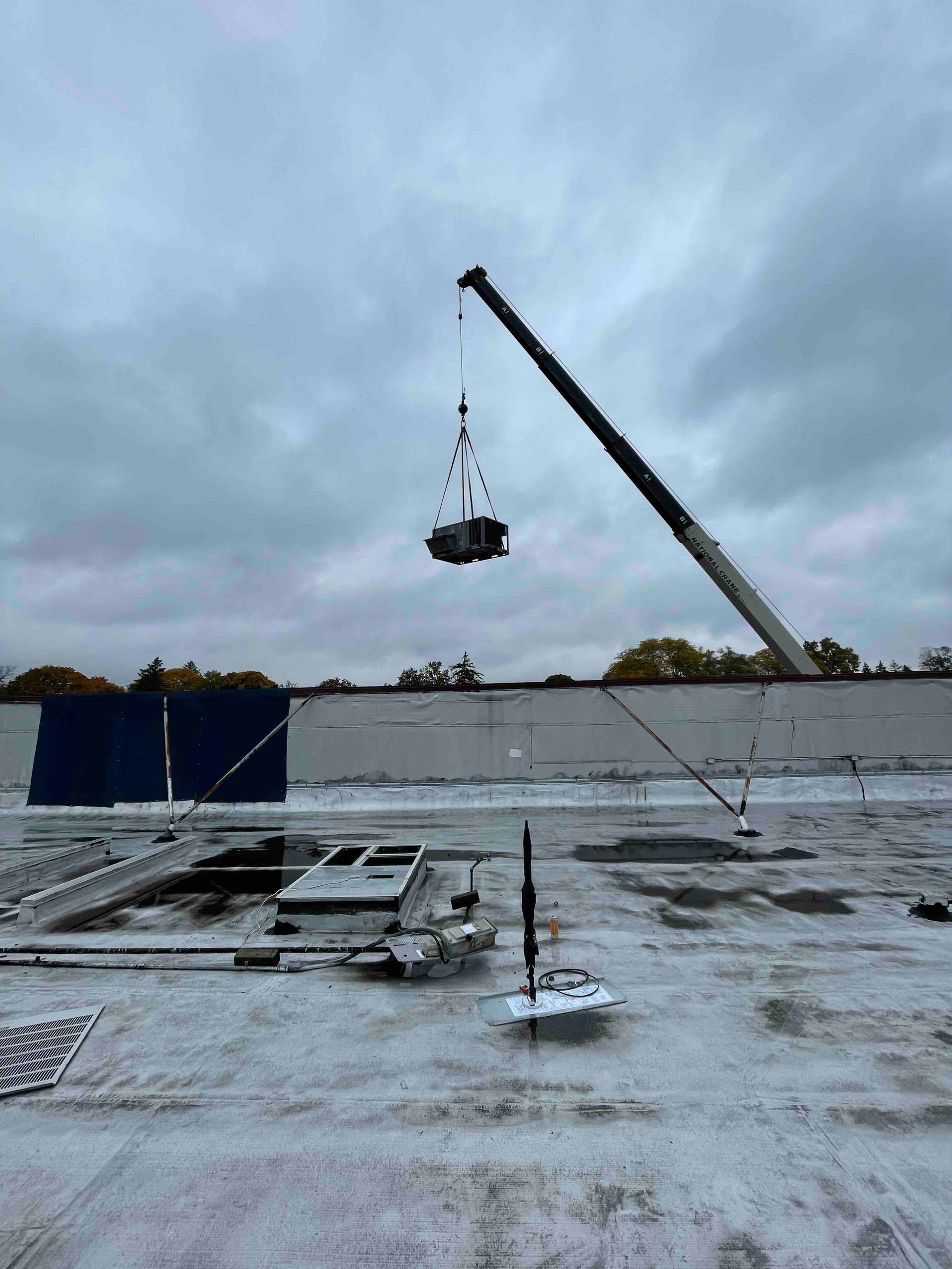 A crane is lifting a large object from the roof of a building.
