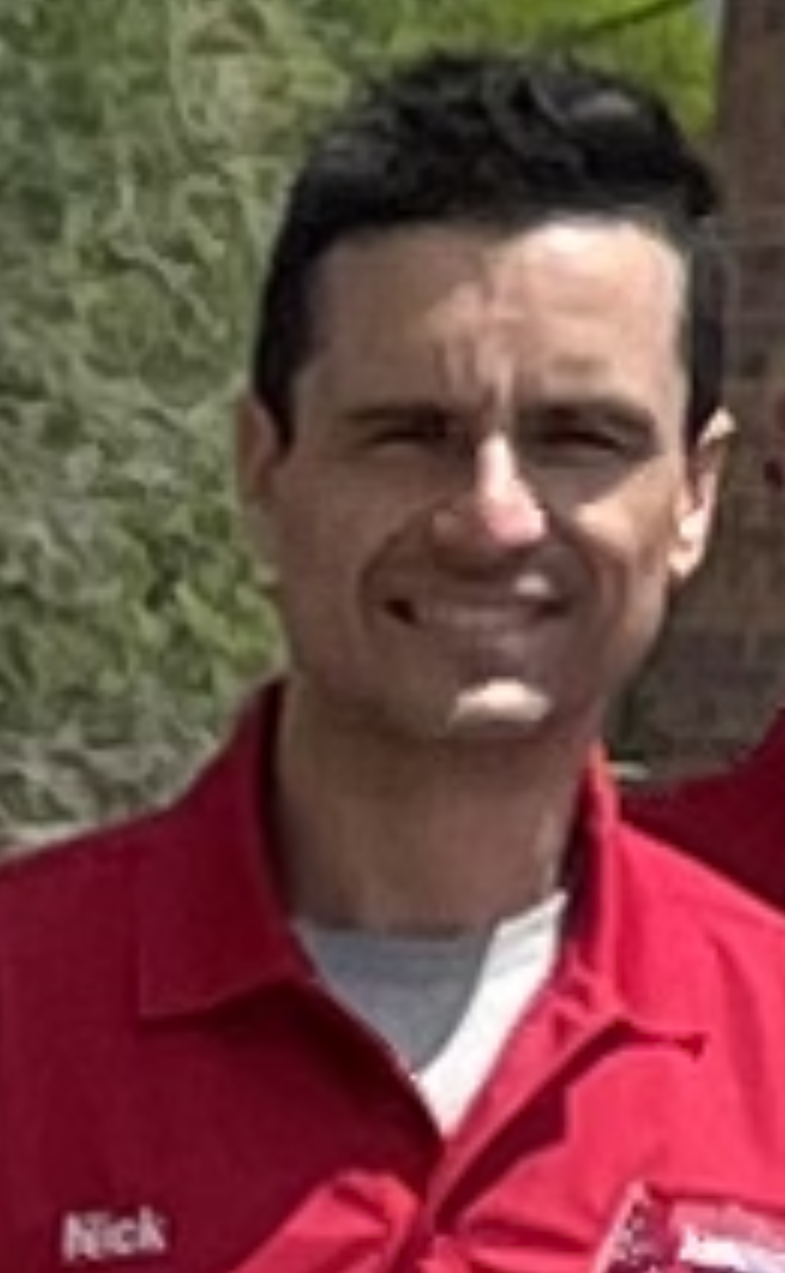A man wearing a red shirt with the name nick on it