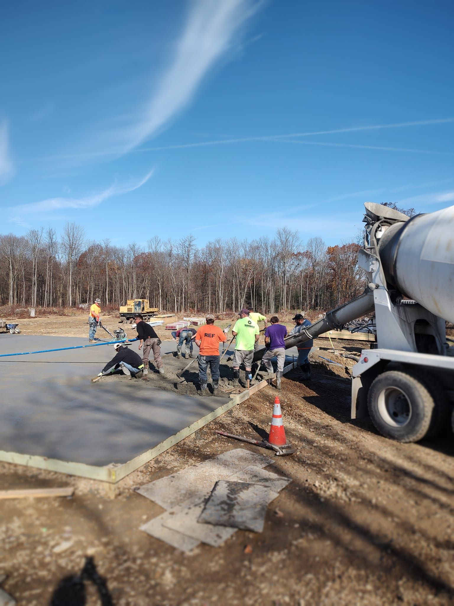 A group of construction workers are standing in front of a concrete mixer truck.