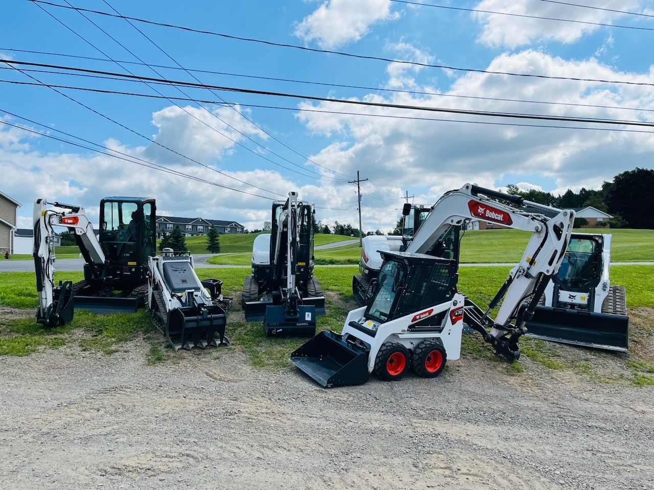 A group of construction vehicles are parked in a dirt lot.