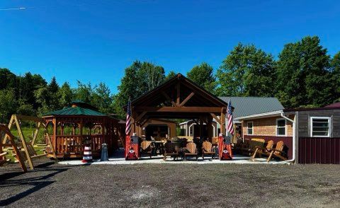 A house with a gazebo and a picnic table in front of it.