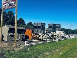 A row of horse trailers are parked in a grassy field.