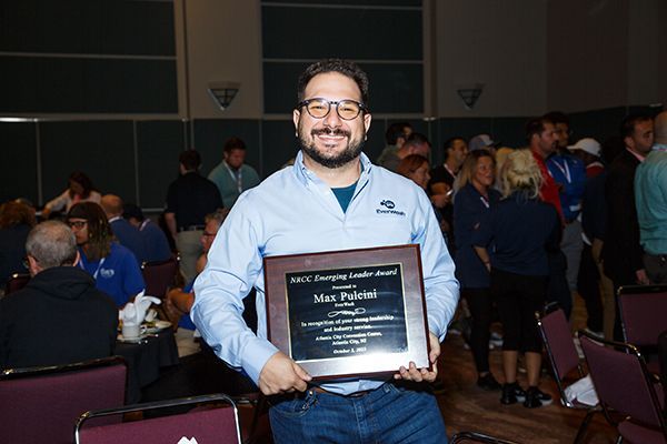Man holding a plaque and smiling at an indoor awards event