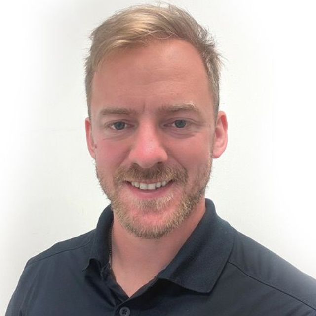 Portrait of a smiling man in a dark polo shirt against a plain white background
