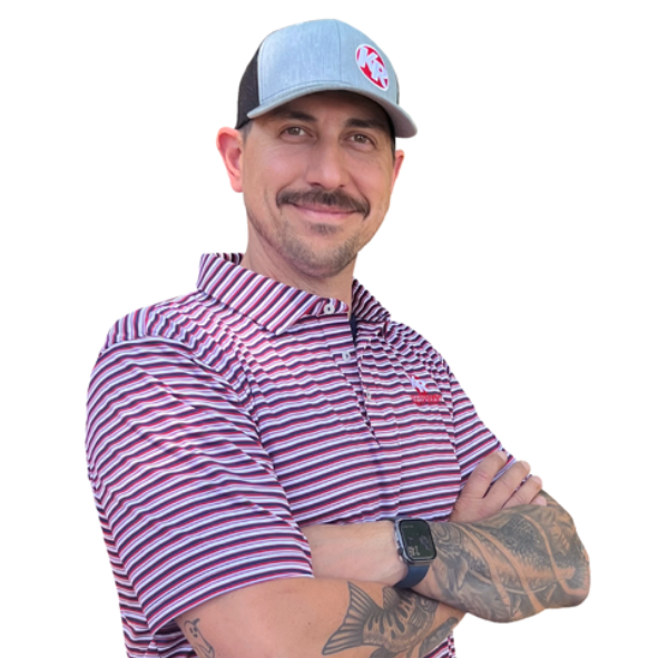 Man, named Phil Donnelly, in a striped shirt and blue cap, arms crossed, standing against a white background.