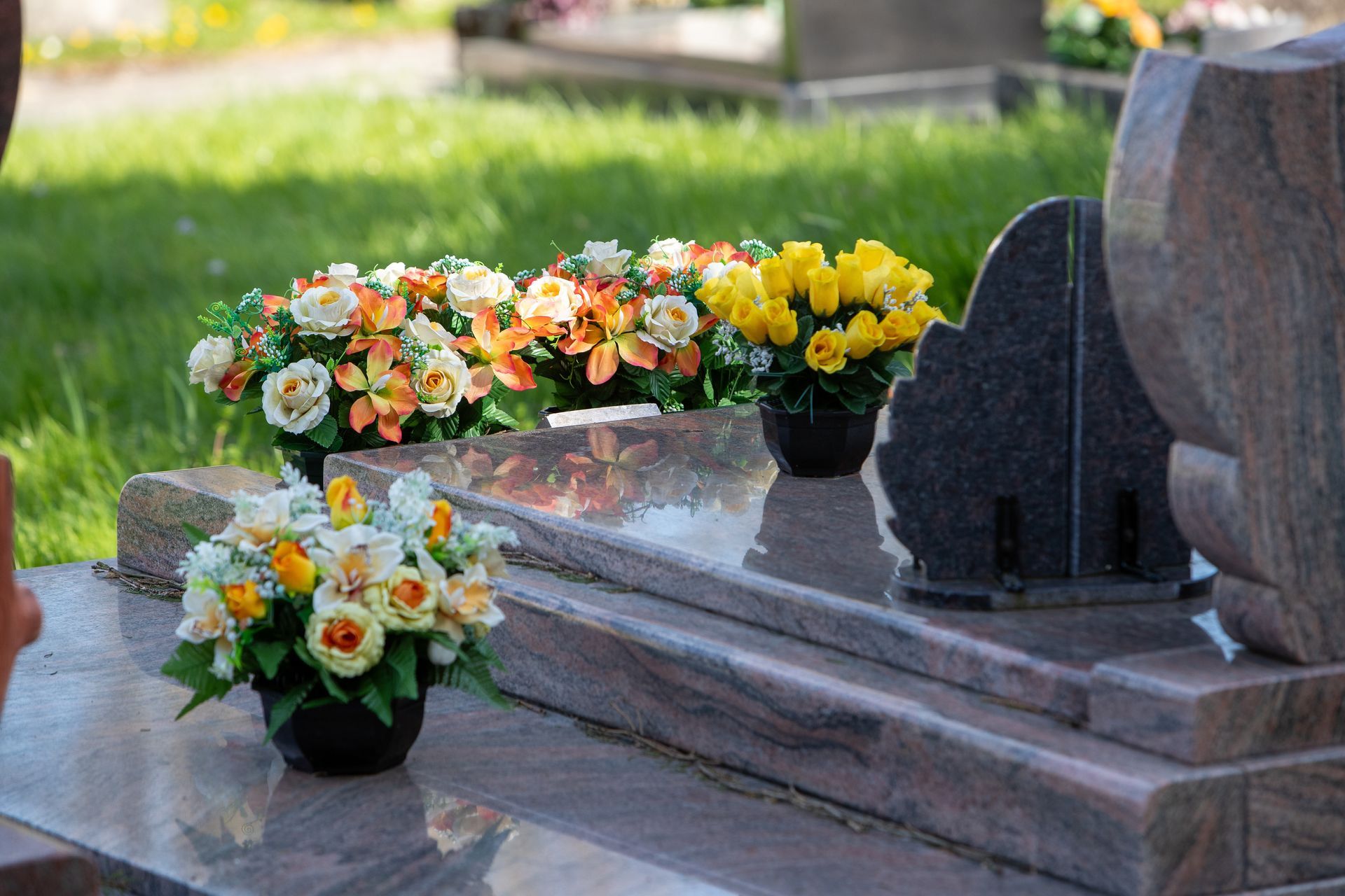 Colorful flowers in vases placed on a grave, symbolizing remembrance and honoring the deceased.