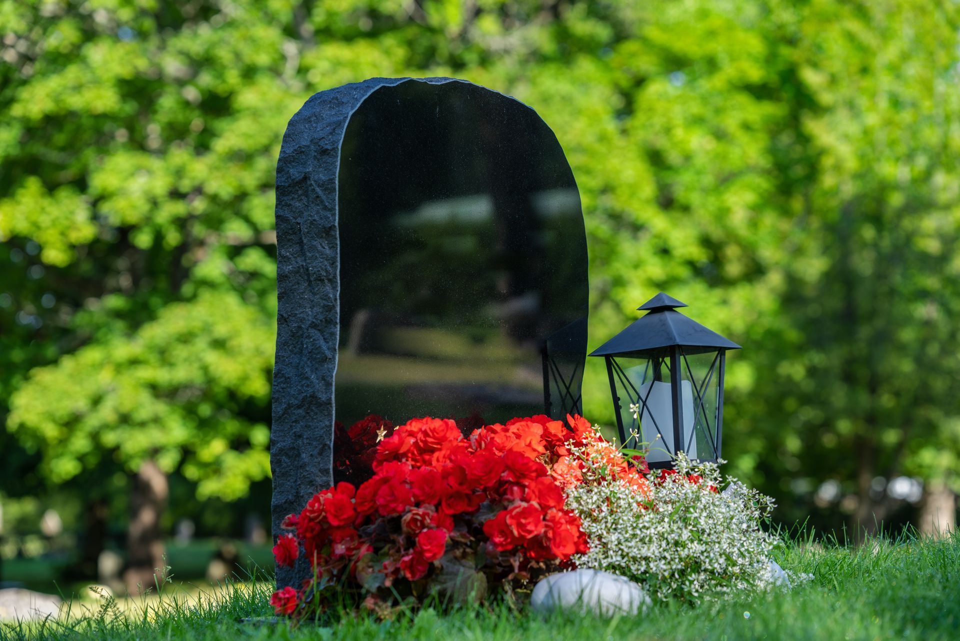 Black gravestone with red and white flowers and without a name inscription.