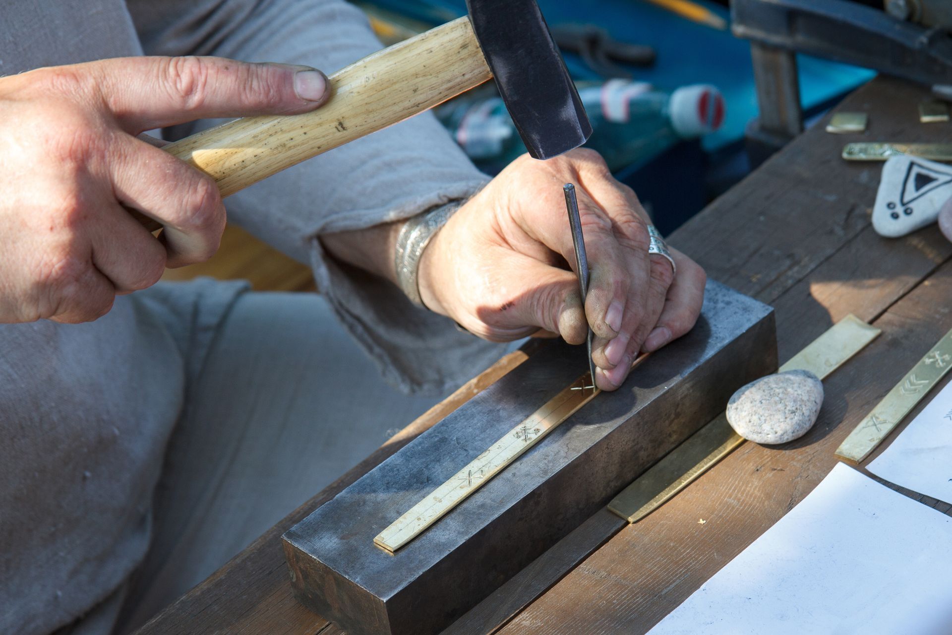 A close-up of a craftsman using tools to shape a piece of granite on a workbench