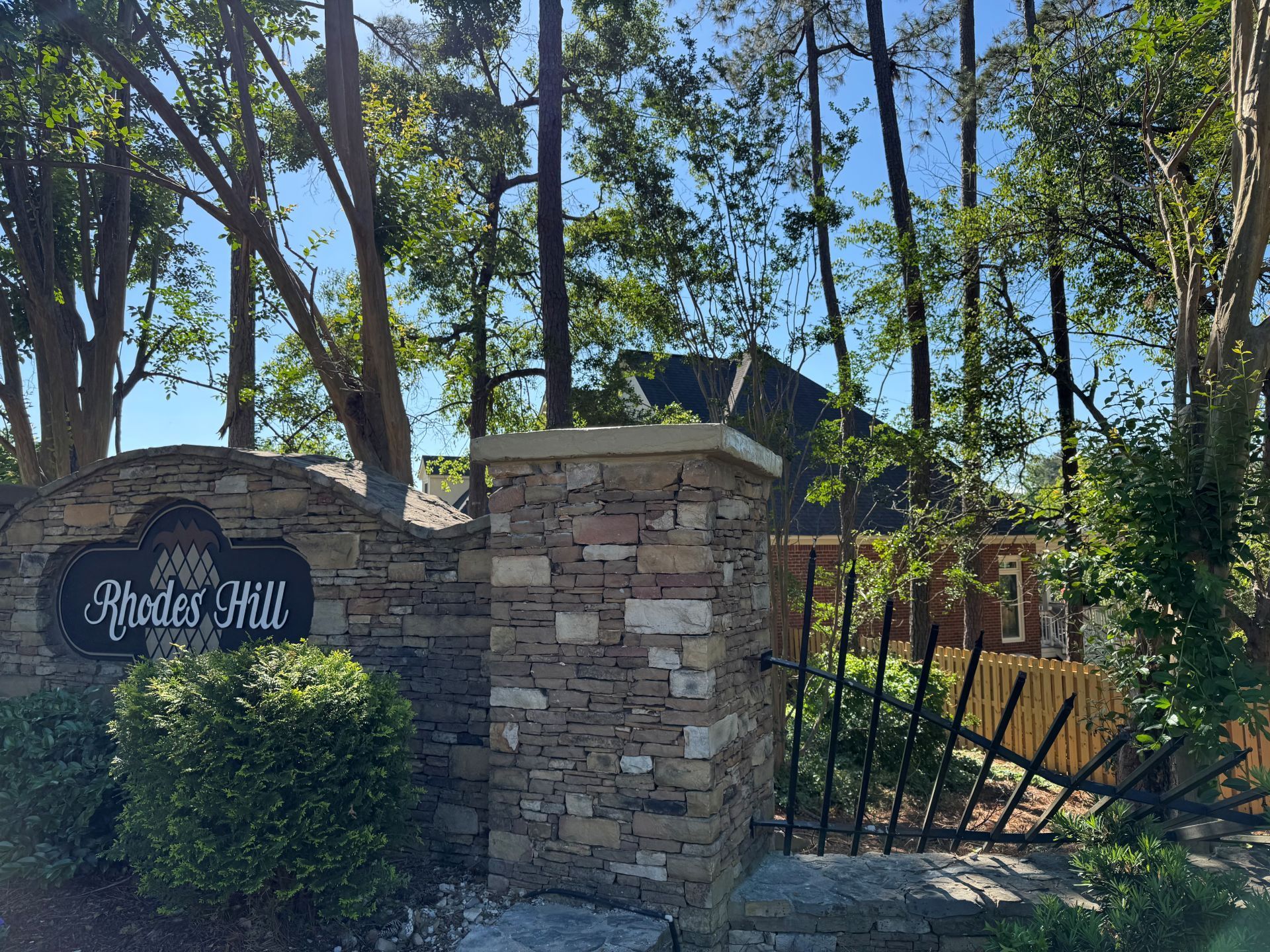 Stone entrance sign reading “Chambers Hill” beside a black gate and trees in sunlight