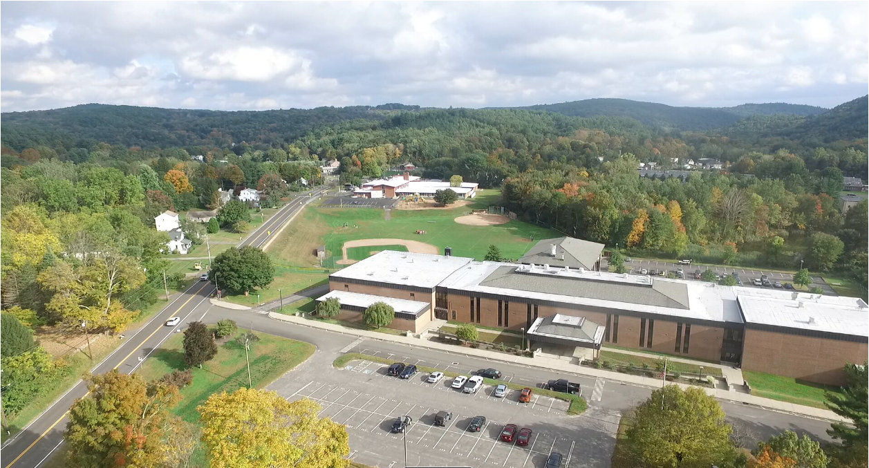 An aerial view of a school with a lot of cars parked in front of it.