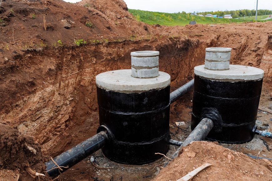 Two septic tanks are being built in a dirt field.