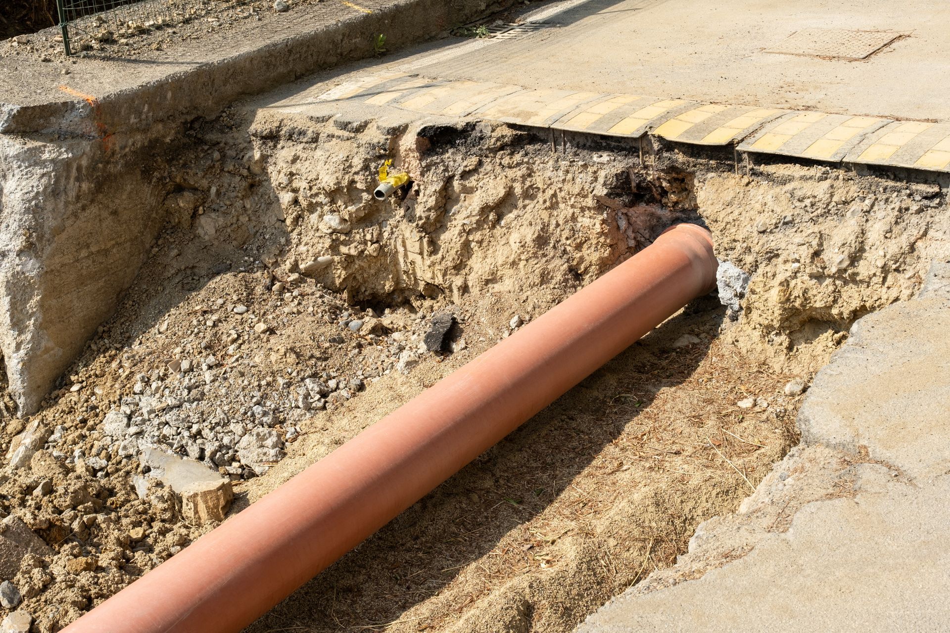 An orange pipe is laying in the dirt on the ground