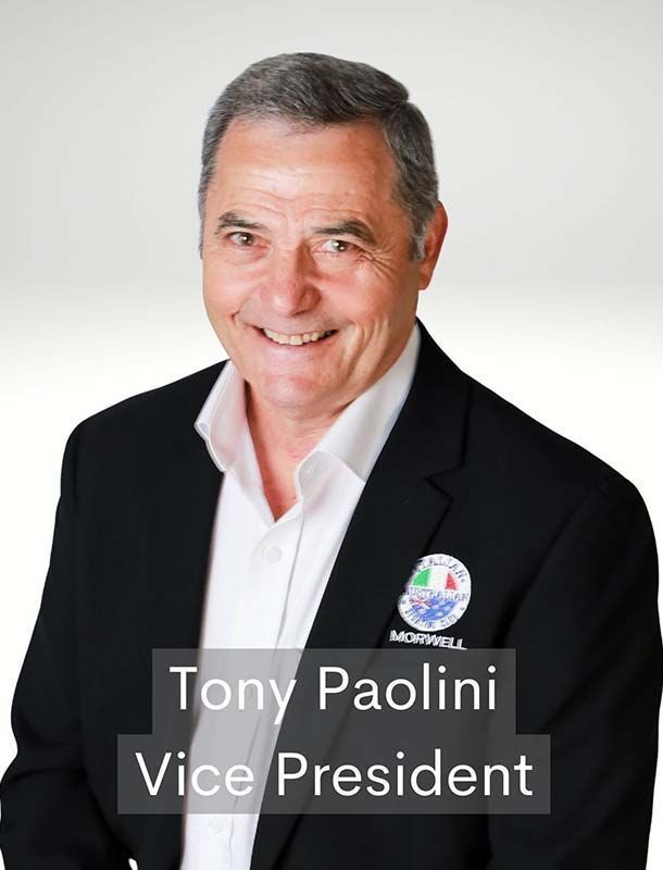Portrait of Tony Paolini in a black blazer and white shirt, smiling against a light background