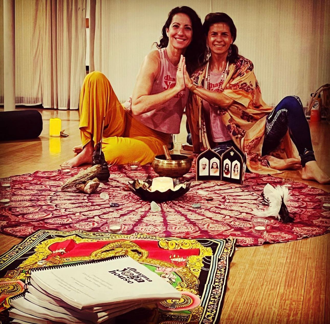 two women are sitting on the floor with their hands together