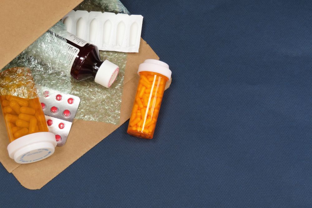 A cardboard box filled with bottles of pills and bottles of syrup.