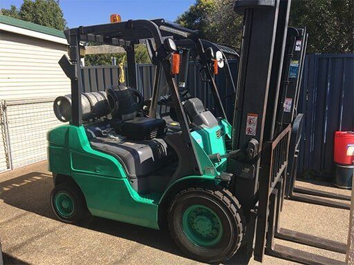Green Forklift is Parked in Front of a Fence — Bundaberg Forklift Repairs Hervey Bay, QLD