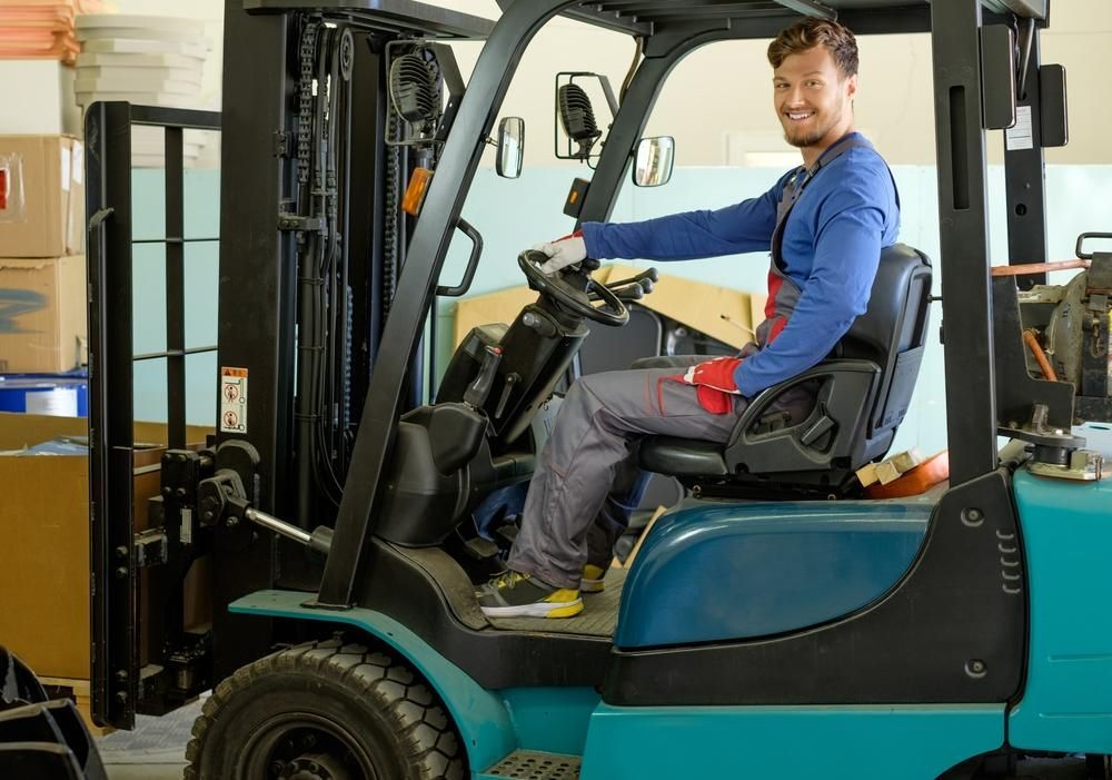 Man is Sitting in a Forklift in a Warehouse — Bundaberg Forklift Repairs Gin Gin, QLD