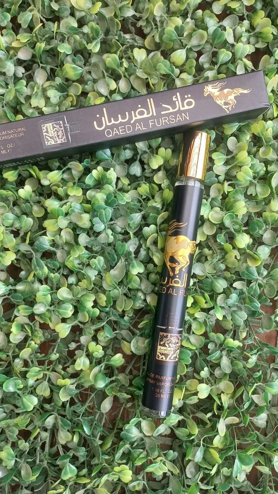 Un perfume en spray de viaje de color negro y su caja a juego con texto dorado 