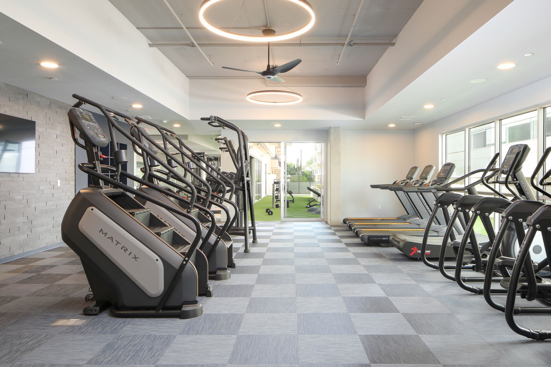 Modern gym interior with treadmills, elliptical machines, and bright windows
