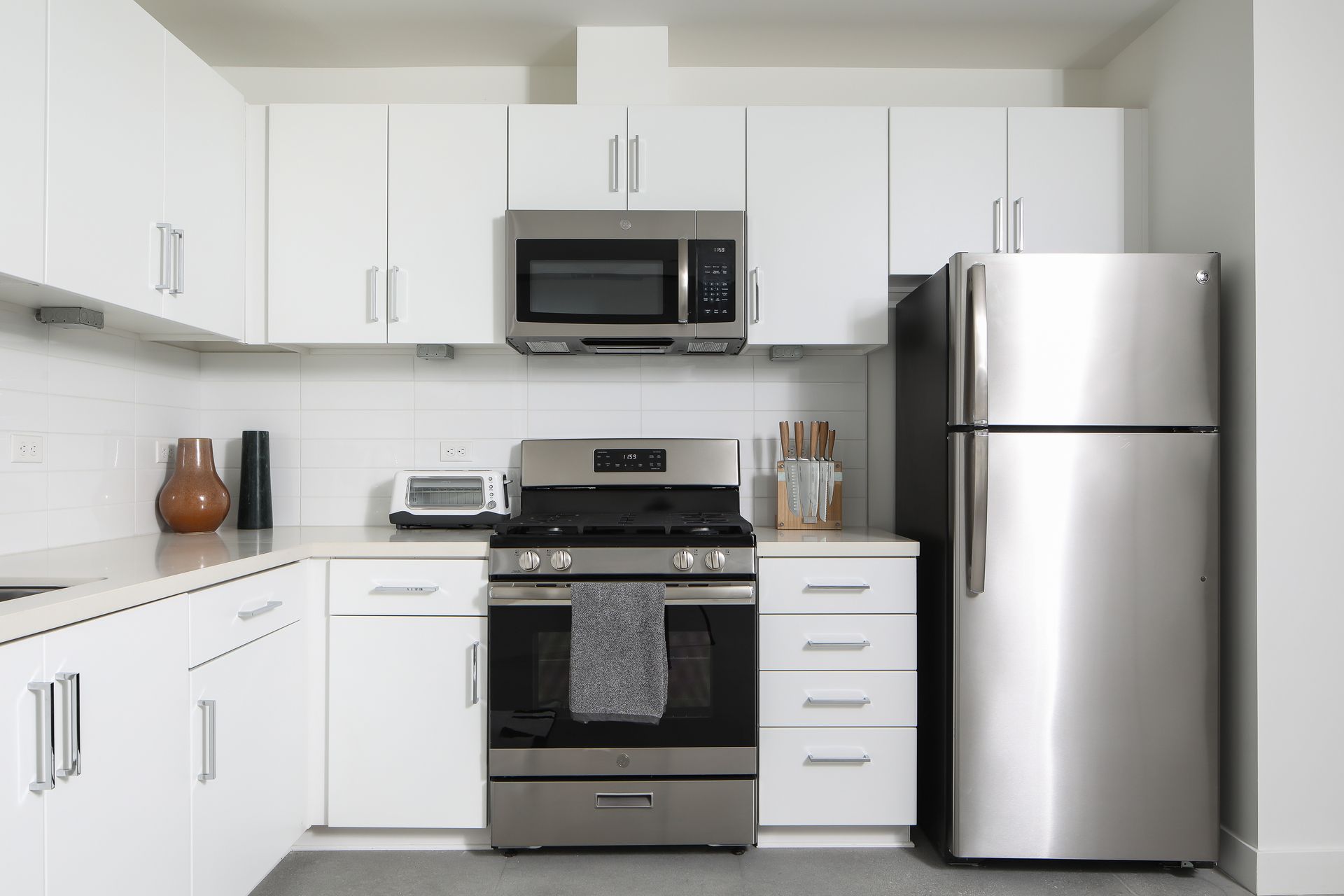 Modern white kitchen with stainless steel appliances and dark countertops