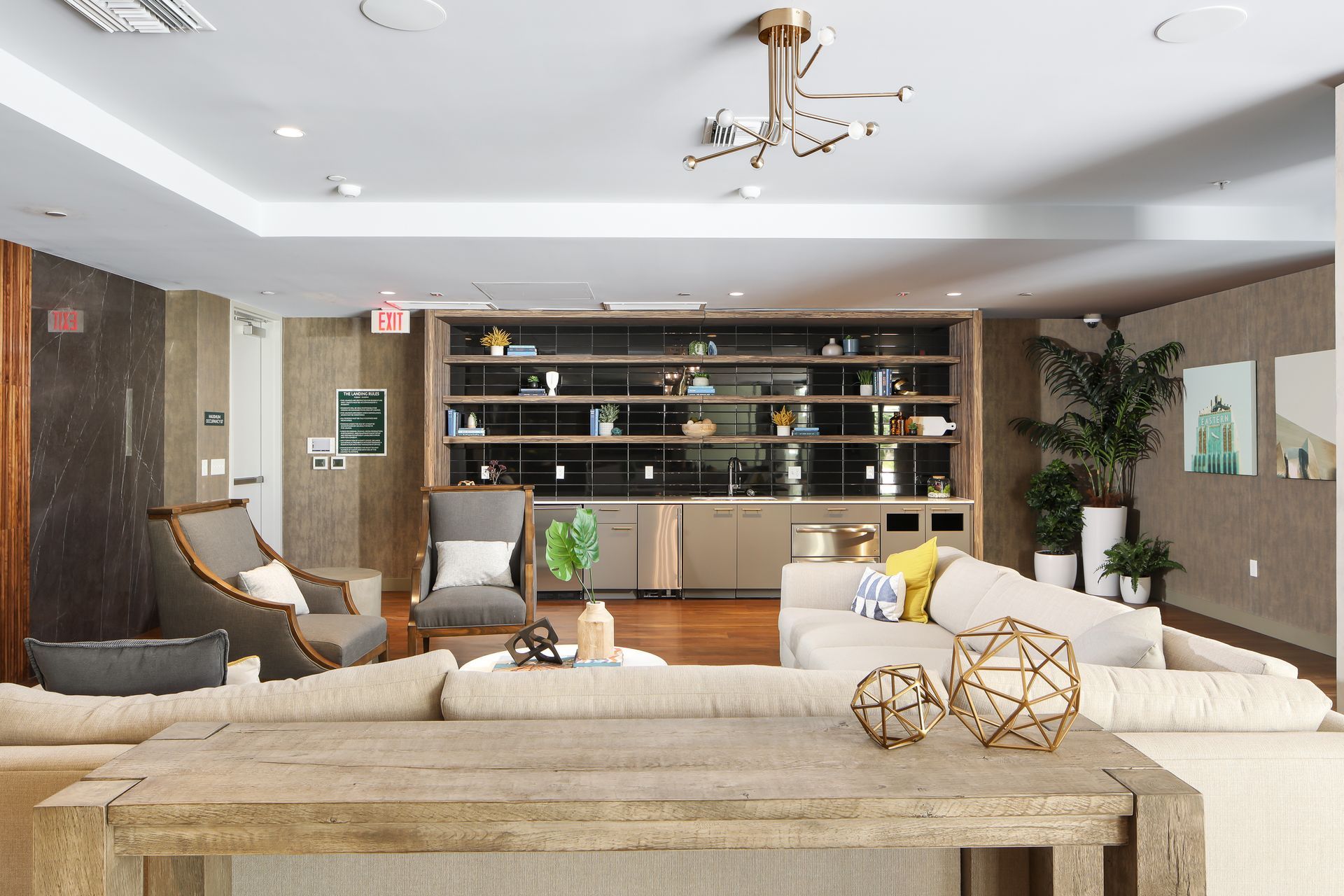 Modern living room with beige sectional, wood shelving, fireplace, and ceiling fan in a bright open space