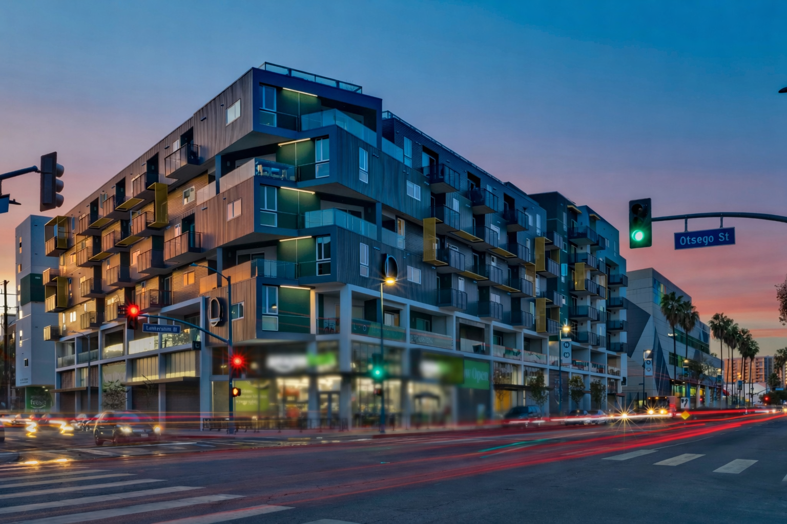 Modern apartment building on a city corner at dusk with lit windows and traffic light trails
