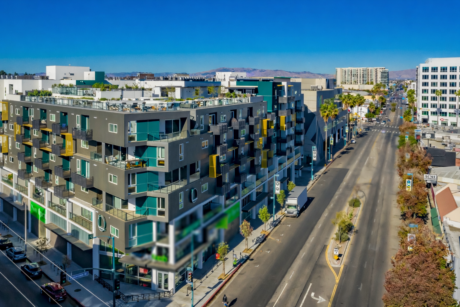 Modern apartment buildings lining a broad city street on a sunny day