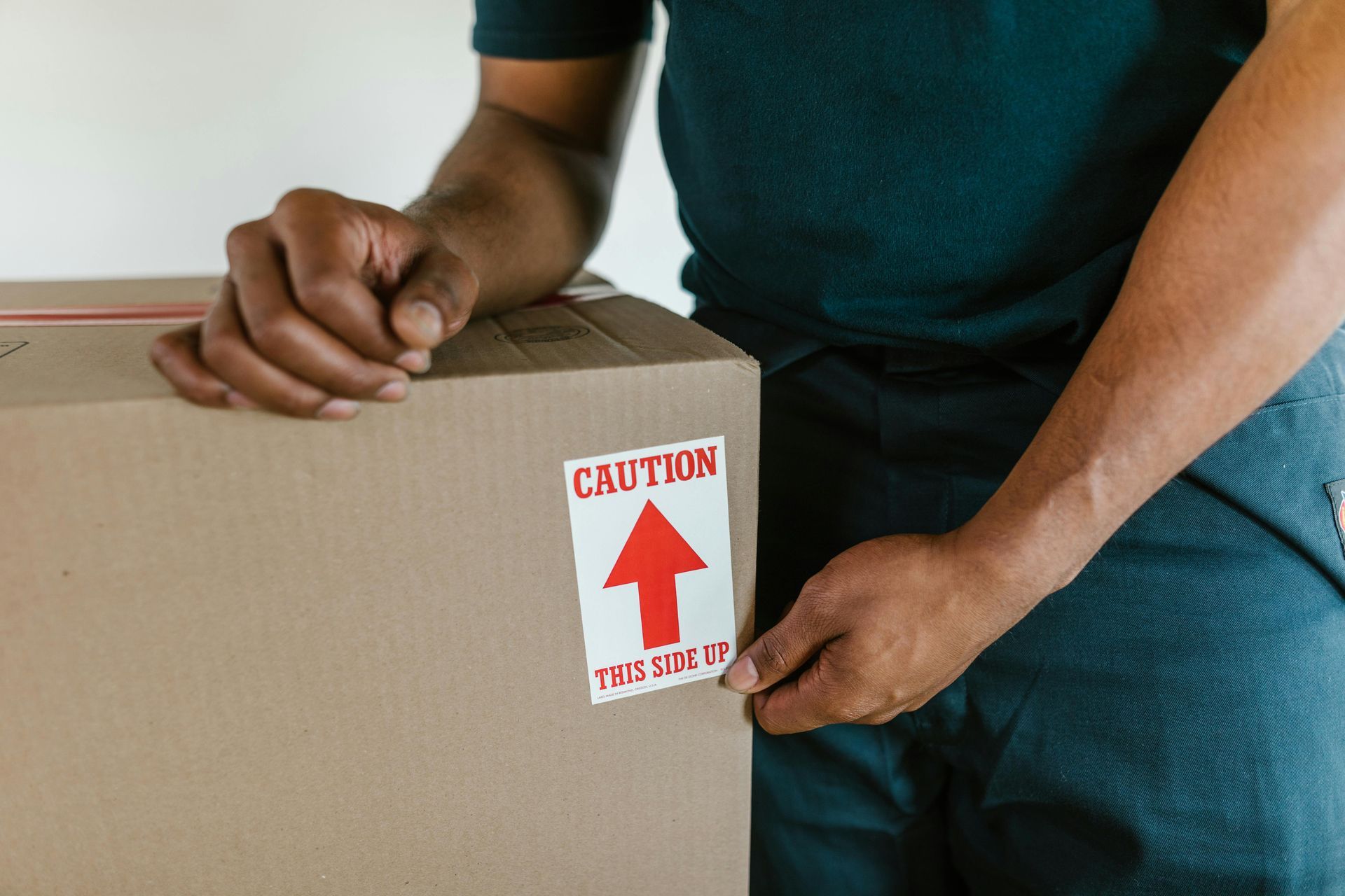 A man is putting a caution sticker on a cardboard box.