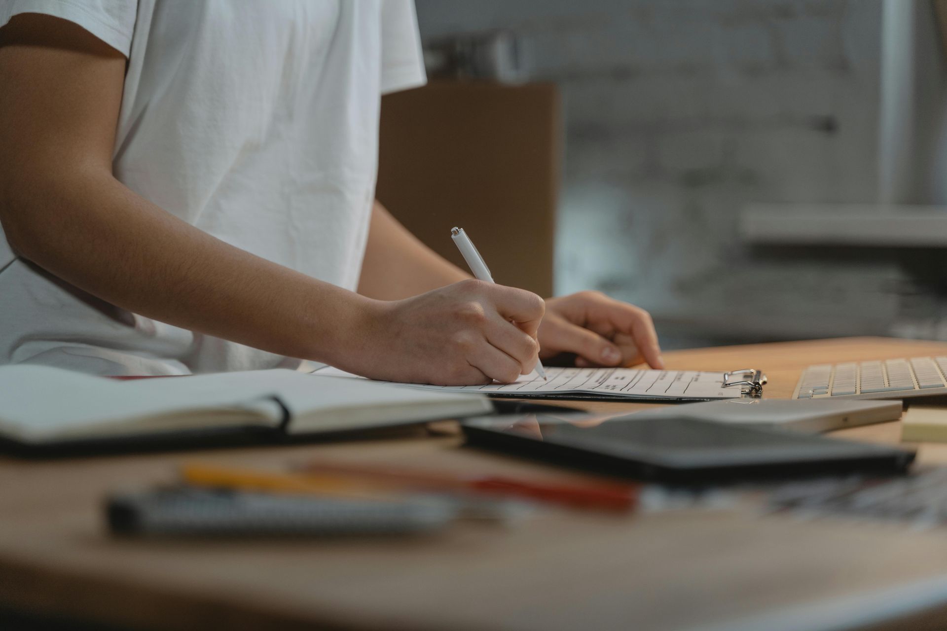 A person is sitting at a desk writing in a notebook.