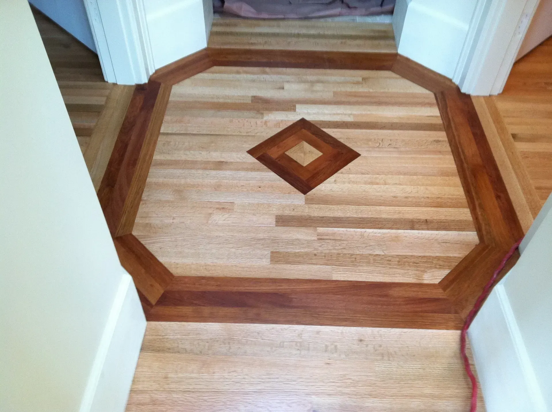 Wood inlaid hallway floor with octagonal border and diamond center medallion at a doorway