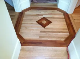 Wood inlaid hallway floor with octagonal border and diamond center medallion at a doorway