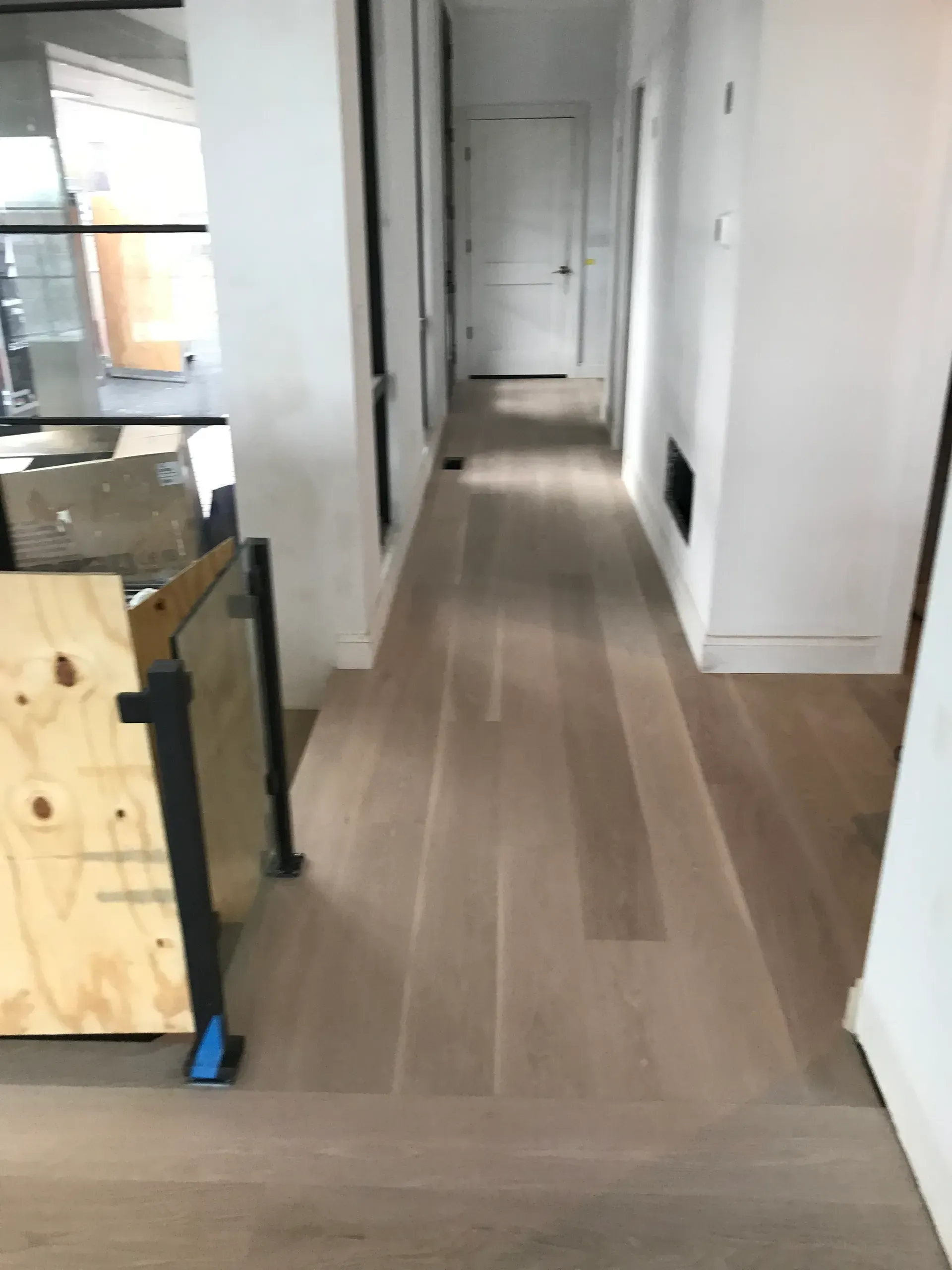 Long hallway with light wood flooring and white walls, viewed from a doorway.