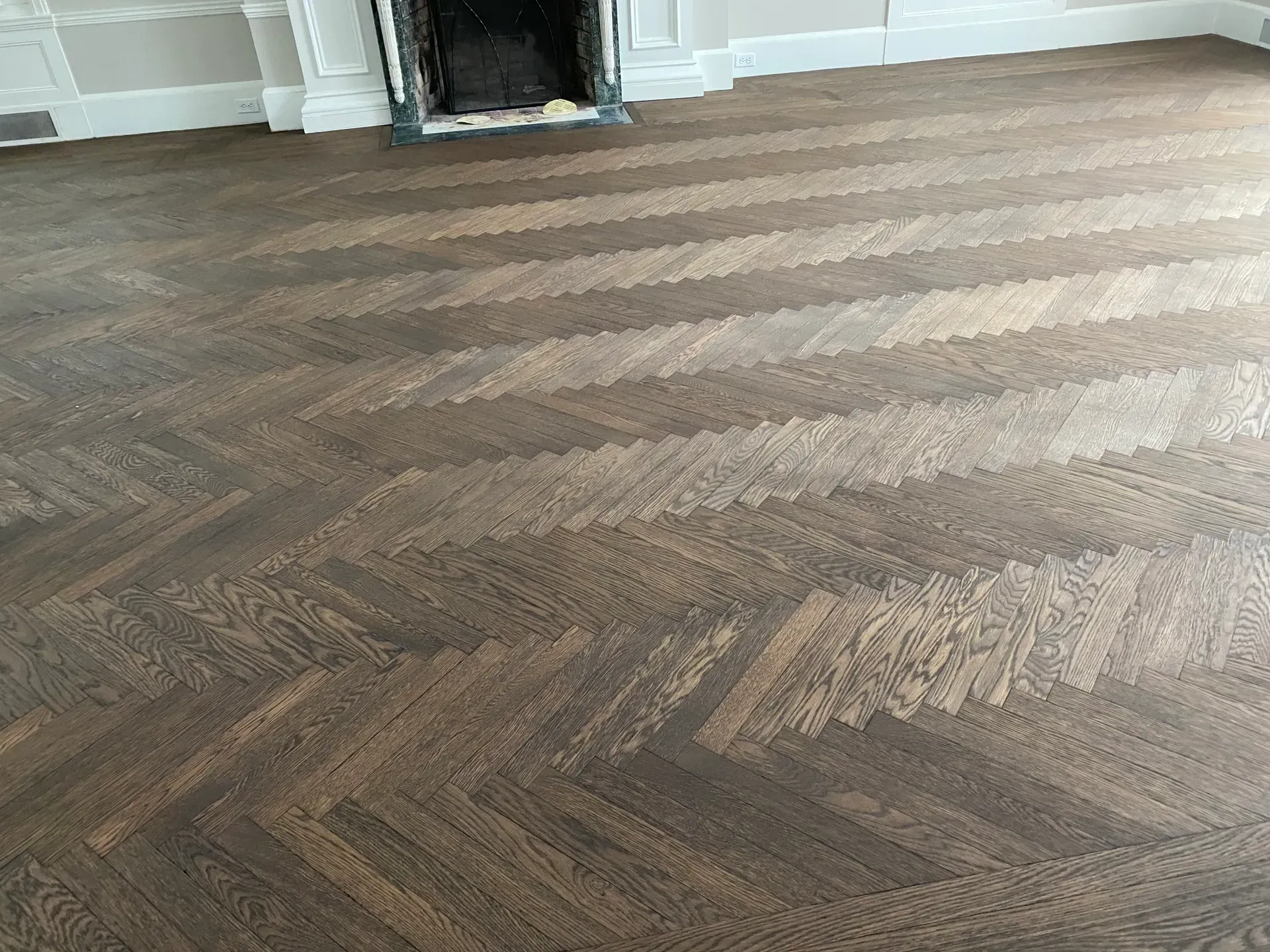 Brown herringbone carpet in an empty room with a fireplace in the background
