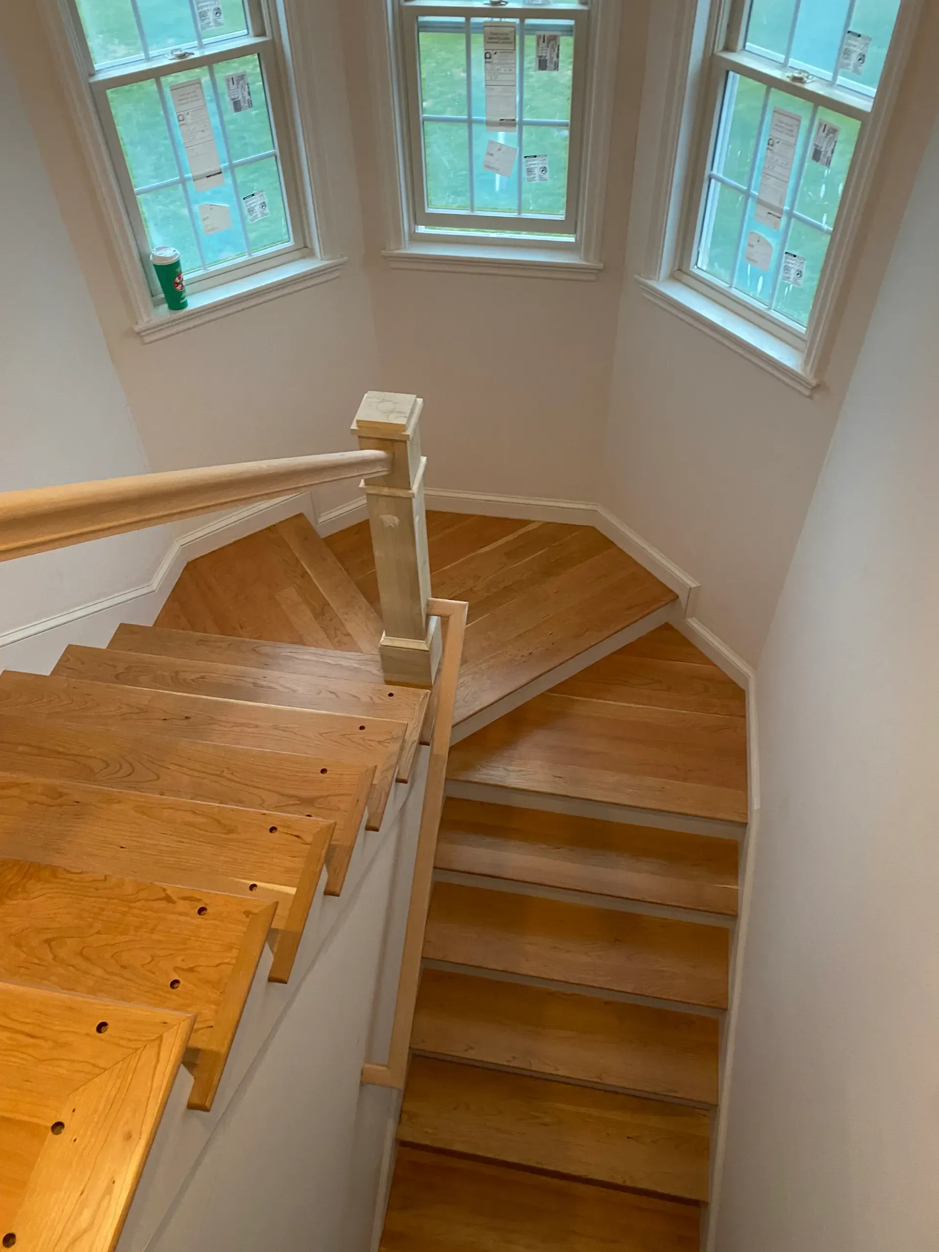 Stairwell with wooden steps and white railing beneath blue-trimmed windows.