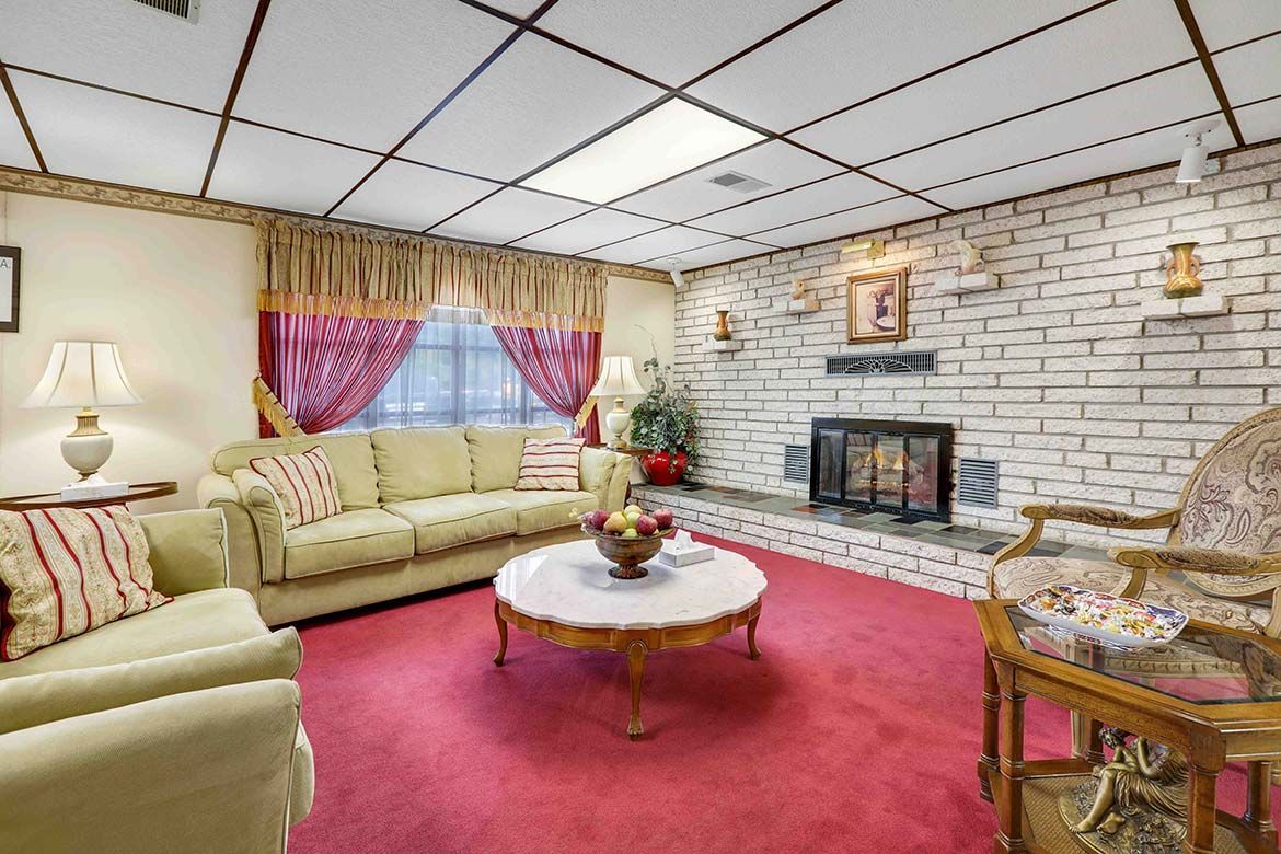 Cozy living room with beige sofas, red carpet, white brick fireplace, and floral curtains